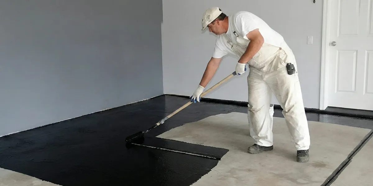 basement waterproofing professional applying waterproof coating to protect a basement floor in Tampa, FL